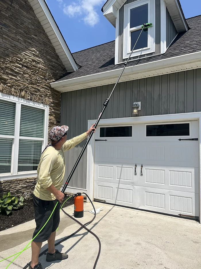 Landon cleaning a garage dormer window with a water-fed pole